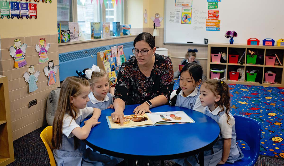 Preschool teacher reading to girls at Villa Maria